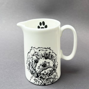 Peut inclure: Une crémier en céramique blanche avec une empreinte de patte noire sur le dessus et une illustration en noir et blanc d'un visage de chien sur le devant.