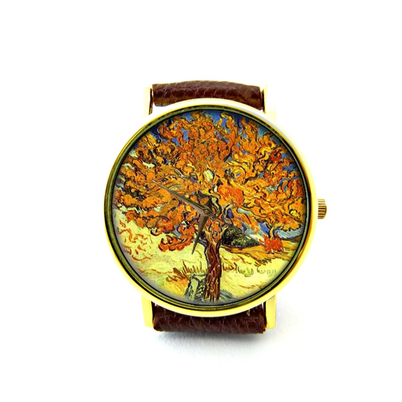 May include: Gold-coloured wristwatch with a dial depicting a tree painting in orange, yellow, and blue, in the style of Van Gogh. It has a brown leather strap.