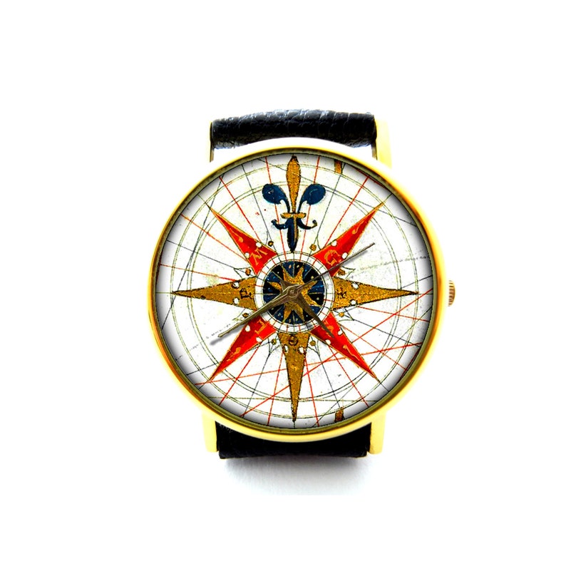 Peut inclure: Une montre dor&eacute;e avec un bracelet en cuir noir. Le cadran de la montre pr&eacute;sente une rose des vents vintage en rouge, or et bleu sur fond blanc. La montre a une forme ronde classique.