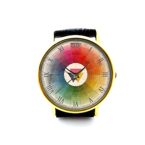 May include: A gold-tone wristwatch with a black leather strap. The watch face features a colourful colour wheel with Roman numeral hour markers.