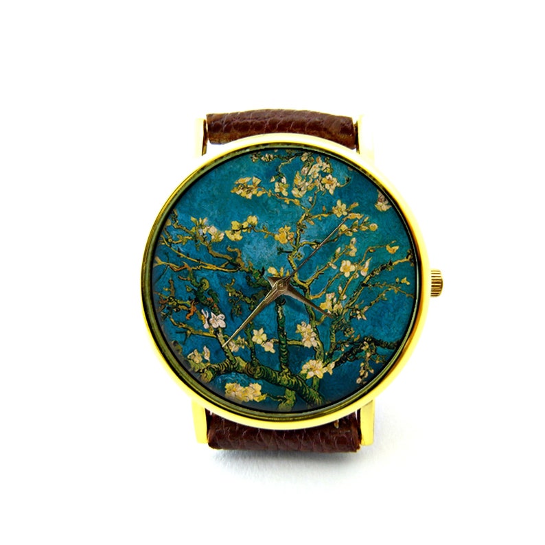 May include: A gold-tone wristwatch with a brown leather band. The watch face features a painting of a blooming almond tree against a blue sky.