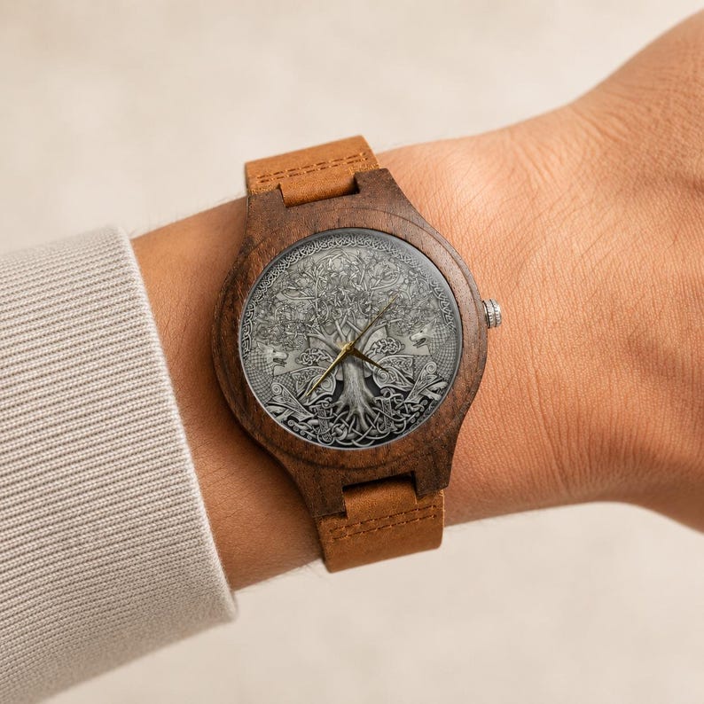 Puede incluir: Un reloj de pulsera de madera con caja circular de color marr&oacute;n oscuro y correa de cuero color canela. La esfera muestra un grabado plateado detallado de un &aacute;rbol con intrincados patrones de nudos y finas manecillas doradas.