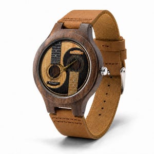 May include: A wooden wristwatch with a brown leather strap. The watch face features a yin-yang design with two acoustic guitars. The watch case is made of dark wood, and the strap is a light brown color.