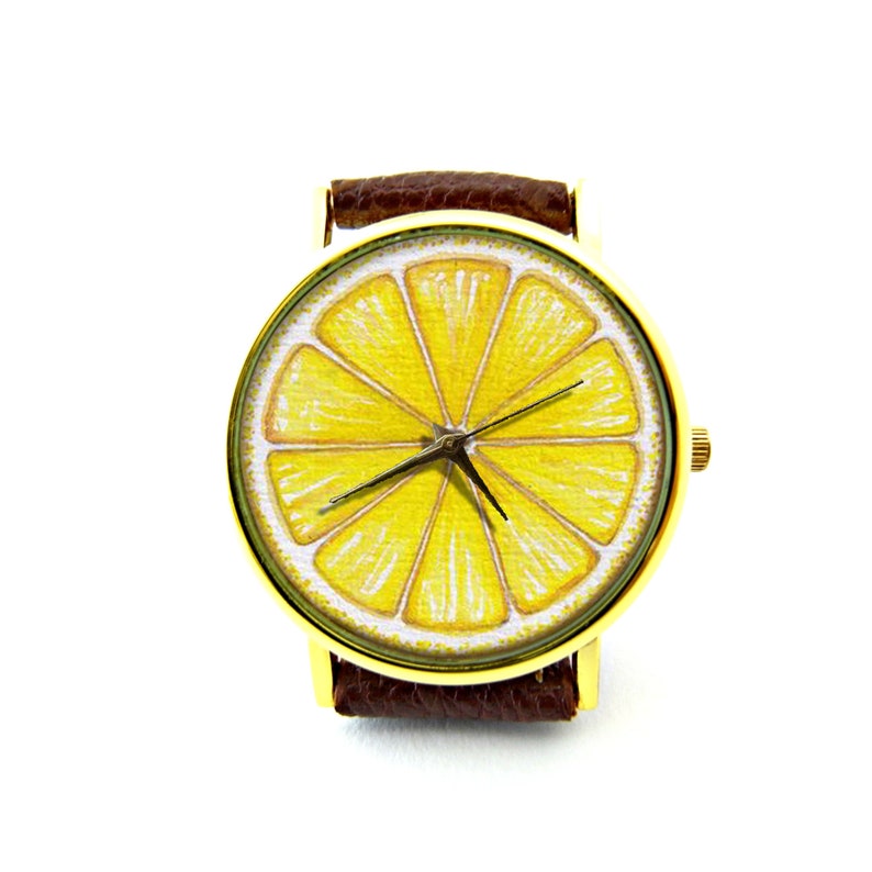 Pode incluir: Um rel&oacute;gio de pulso dourado com uma pulseira de couro marrom. O mostrador do rel&oacute;gio apresenta uma ilustra&ccedil;&atilde;o de uma fatia de lim&atilde;o amarela.