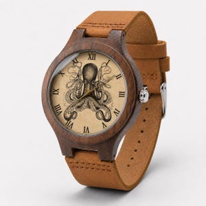 Op de afbeelding: Een houten polshorloge met een donkerbruine ronde kast en een lichtbruine leren band. De wijzerplaat toont een gedetailleerde zwart-witte illustratie van een octopus op een crèmekleurige achtergrond met zwarte Romeinse cijfers.