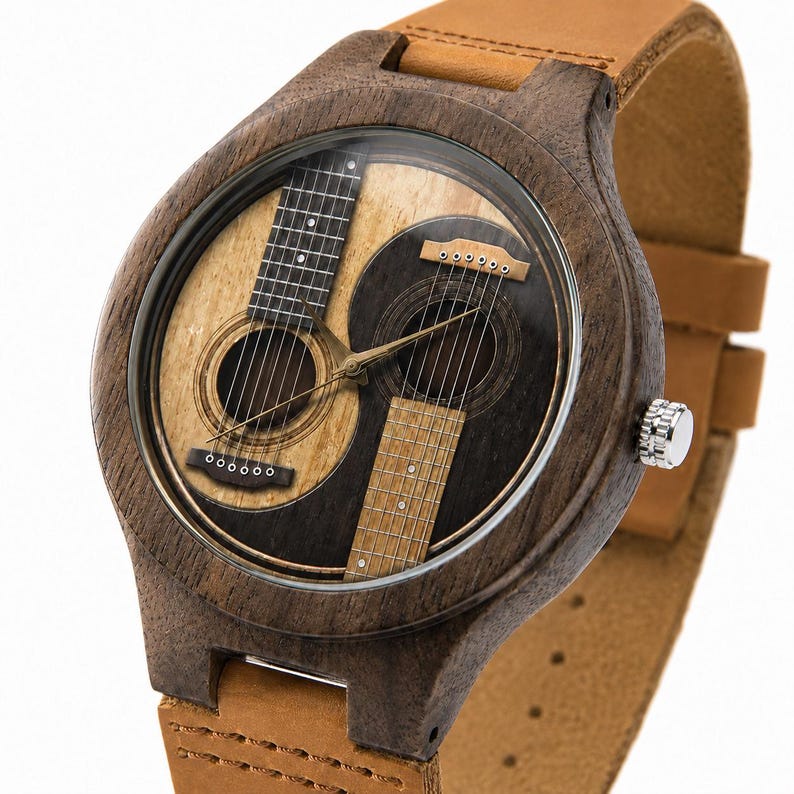 May include: A wooden wristwatch with a unique design featuring two acoustic guitars in a yin-yang arrangement on the watch face. The watch has a brown wooden case, a clear glass face, and a tan leather band. The watch face has a light brown and dark brown color scheme.