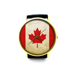 Könnte beinhalten: Eine goldfarbene Armbanduhr mit einem schwarzen Lederarmband und einem Zifferblatt mit der kanadischen Flagge. Die Flagge ist ein rotes Ahornblatt auf weißem Grund mit einem roten und weißen Streifen auf jeder Seite.