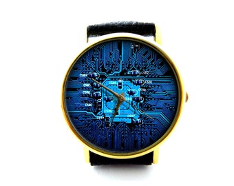 Peut inclure: Une montre-bracelet dorée avec un bracelet en cuir noir. Le cadran de la montre présente un motif de circuit imprimé bleu et noir.