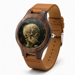 May include: A wooden wristwatch with a brown leather strap. The watch face features a skull smoking a cigarette, with Roman numeral hour markers. The watch case is made of dark wood.