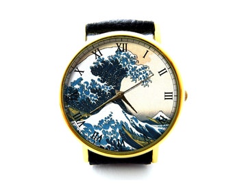 May include: A gold-tone wristwatch with a black leather band features a white face with Roman numeral hour markers and a print of the Great Wave off Kanagawa by Hokusai.