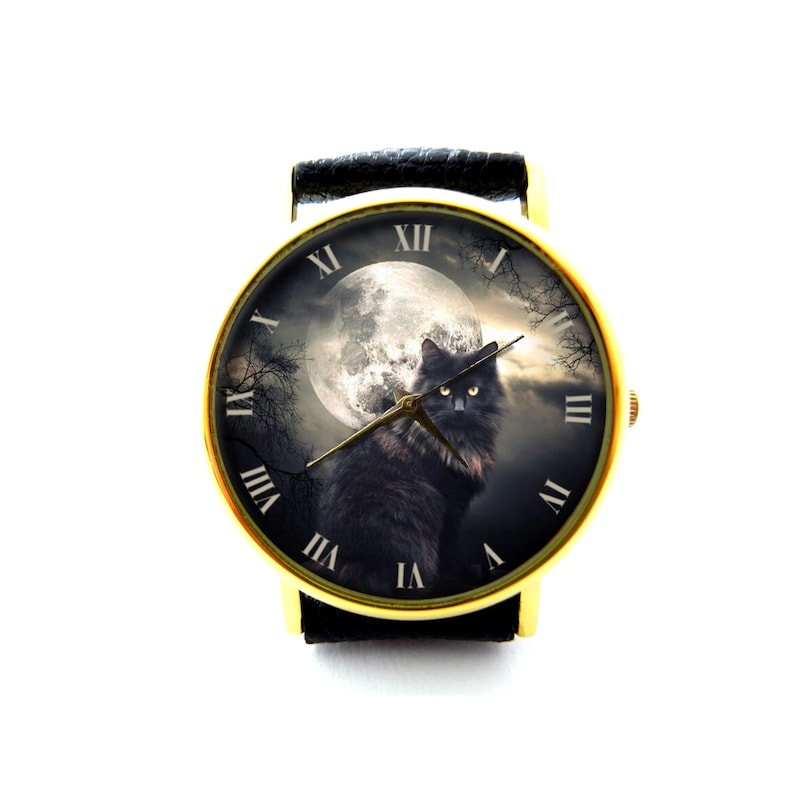 K&ouml;nnte beinhalten: Eine goldfarbene Armbanduhr mit schwarzem Lederarmband zeigt eine schwarze Katze vor dem Hintergrund eines Vollmonds mit r&ouml;mischen Ziffern auf dem Zifferblatt.