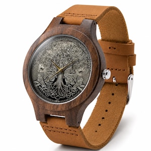 Puede incluir: Un reloj de pulsera con caja de madera marr&oacute;n oscuro y correa de cuero color canela. La esfera presenta una ilustraci&oacute;n gris detallada de un &aacute;rbol con ra&iacute;ces entrelazadas y dos lobos, con manecillas de hora y minuto de color dorado.