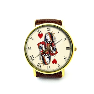 May include: A gold-tone wristwatch with a brown leather band. The watch face features a white background with Roman numeral hour markers and a playing card image of the Queen of Hearts.
