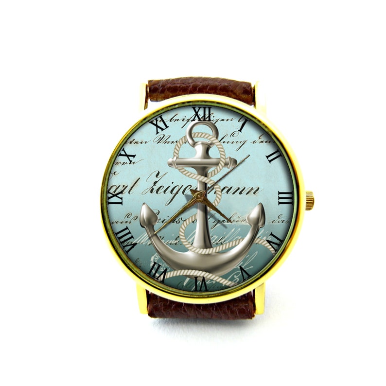 K&ouml;nnte beinhalten: Eine goldfarbene Armbanduhr mit einem braunen Lederarmband. Das Zifferblatt der Uhr hat einen blauen und wei&szlig;en Hintergrund mit einem silbernen Anker- und Seildesign. Das Zifferblatt der Uhr hat auch r&ouml;mische Ziffern als Stundenmarkierungen und den Text "Carl Zeigmann".