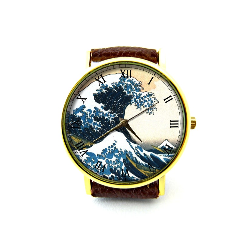 May include: A gold wristwatch with a brown leather band features a white face with Roman numeral hour markers and a depiction of the Great Wave off Kanagawa by Katsushika Hokusai.