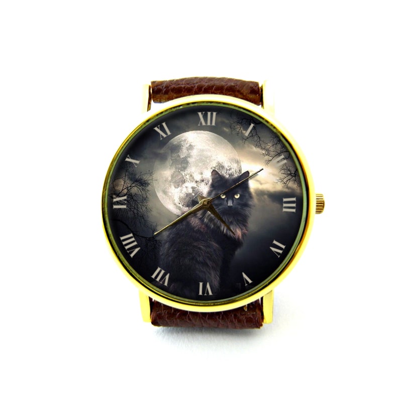 K&ouml;nnte beinhalten: Eine goldfarbene Armbanduhr mit braunem Lederarmband zeigt eine schwarze Katze vor dem Hintergrund eines Vollmonds und eines dunklen, bew&ouml;lkten Himmels. R&ouml;mische Ziffern markieren die Stunden um das Zifferblatt.