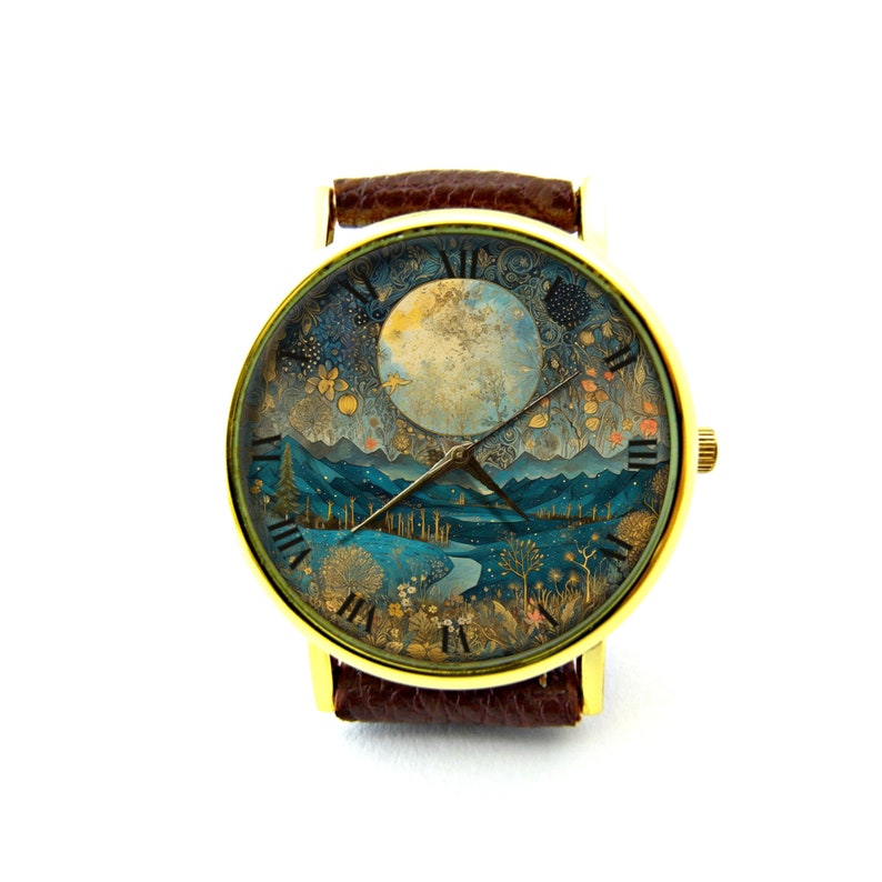 Puede incluir: Un reloj de pulsera de tono dorado con una correa de cuero marr&oacute;n. La esfera del reloj presenta una ilustraci&oacute;n detallada de un paisaje iluminado por la luna con luna llena, monta&ntilde;as y &aacute;rboles.