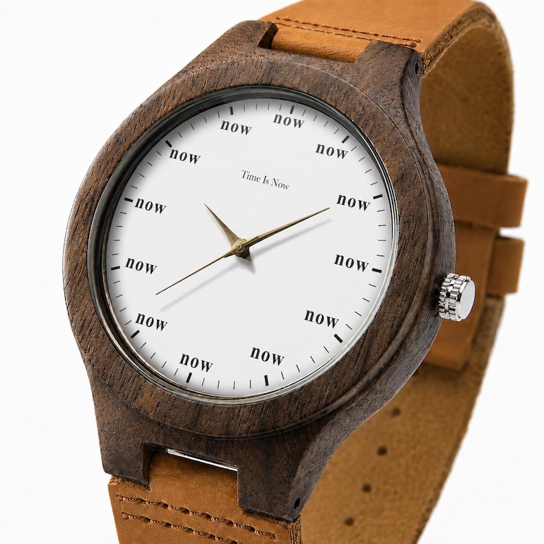 K&ouml;nnte beinhalten: Eine Holzarmbanduhr mit wei&szlig;em Zifferblatt und braunem Lederarmband. Das Zifferblatt zeigt das Wort "now" anstelle von Zahlen, mit dem Text "Time Is Now" in der Mitte. Das Uhrengeh&auml;use ist dunkelbraun.