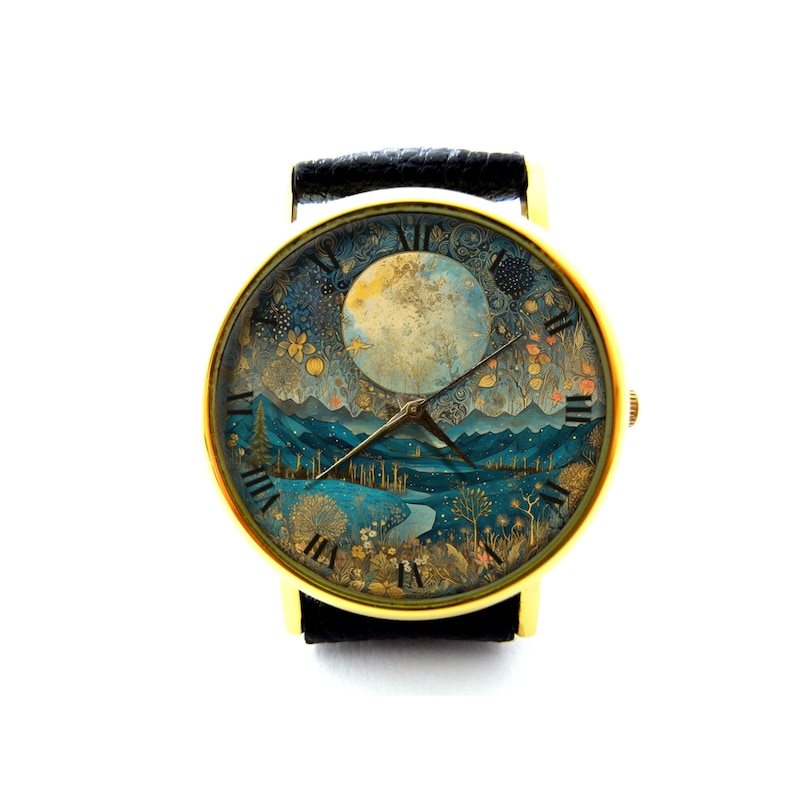 Puede incluir: Un reloj de pulsera dorado con una correa de cuero negro. La esfera del reloj presenta una ilustraci&oacute;n detallada de un paisaje iluminado por la luna con una luna llena, monta&ntilde;as y &aacute;rboles.