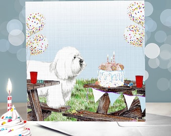 May include: A white Bichon Frise dog sits at a picnic table with a birthday cake and balloons. The cake is decorated with sprinkles and candles. The dog is looking at the cake.