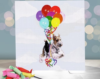 Puede incluir: Un perro fox terrier de pelo duro blanco y marrón está volando con un montón de globos de colores. Los globos son rojos, rosas, morados, amarillos, verdes y azules. El perro lleva una cinta de arcoíris.