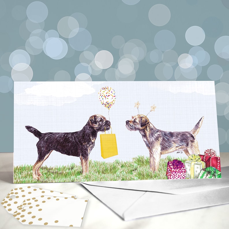 May include: A birthday card featuring two brown and black Border Collie dogs. One dog is holding a yellow gift bag and the other dog is wearing a party hat with stars. The card has a blue sky background with white clouds and a colorful balloon.