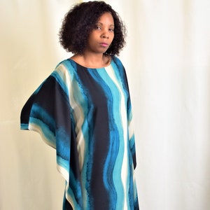 May include: A long, flowing blue and white striped dress with a wide, flowing sleeve. The dress has a watercolor-like design with shades of blue, white, and black.