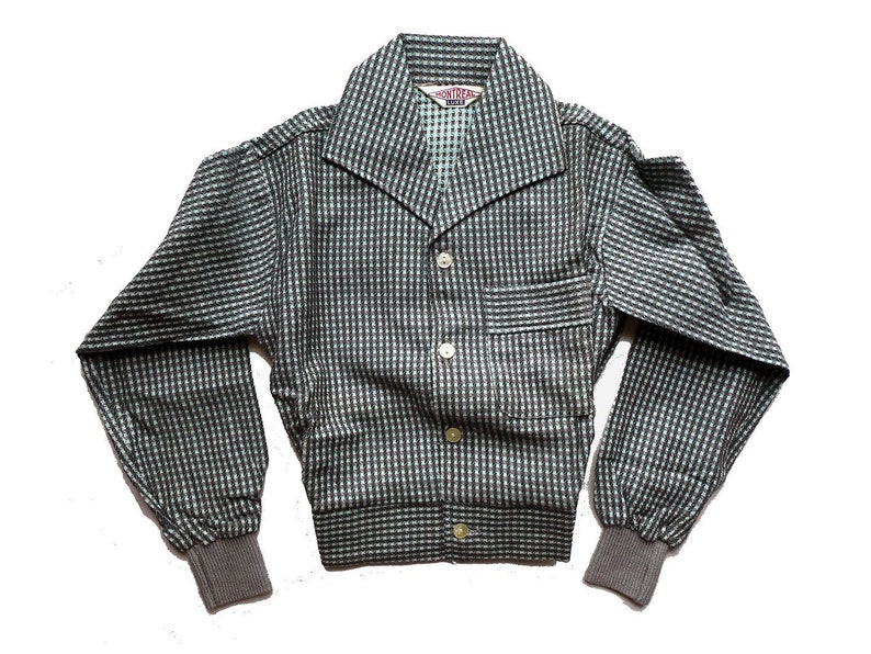 May include: A gray and white checkered button-up shirt with a long sleeve and a collar. The shirt has a pocket on the left side and a label that reads "Montreal" on the front.