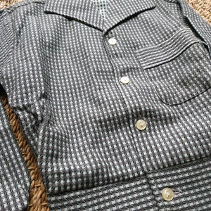May include: A black and white checkered button-up shirt with a long sleeve and a pocket on the left side.
