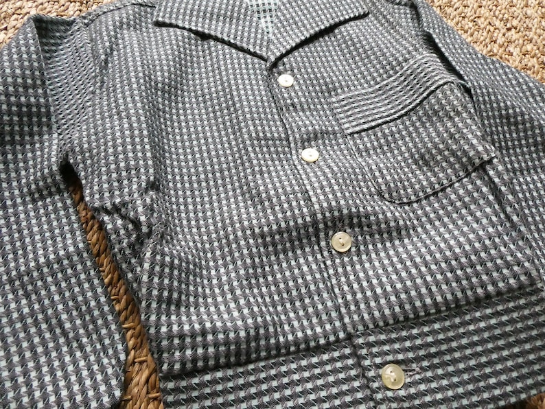 May include: A black and white checkered button-up shirt with a long sleeve and a pocket on the left side.