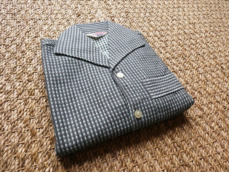 May include: A black and white checkered shirt with a collar and button closure. The shirt has a pocket on the left side and a label that reads "MONTY HALL".