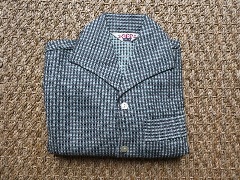 May include: A blue and black checkered shirt with a button-up front and a collar. The shirt has a pocket on the left side and a label that reads "Montreal Luxe".