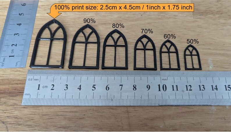 May include: Black miniature arched window frames in varying sizes, ranging from 50% to 100% print size. The largest frame measures 1 inch x 1.75 inches. A ruler is placed below the frames for scale.