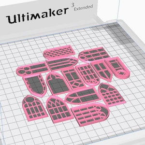 May include: A collection of pink 3D-printed window-shaped objects with various designs, including arched, rectangular, and pointed shapes. The objects are arranged on a grid-patterned surface, with the "Ultimaker" logo visible in the top left corner.