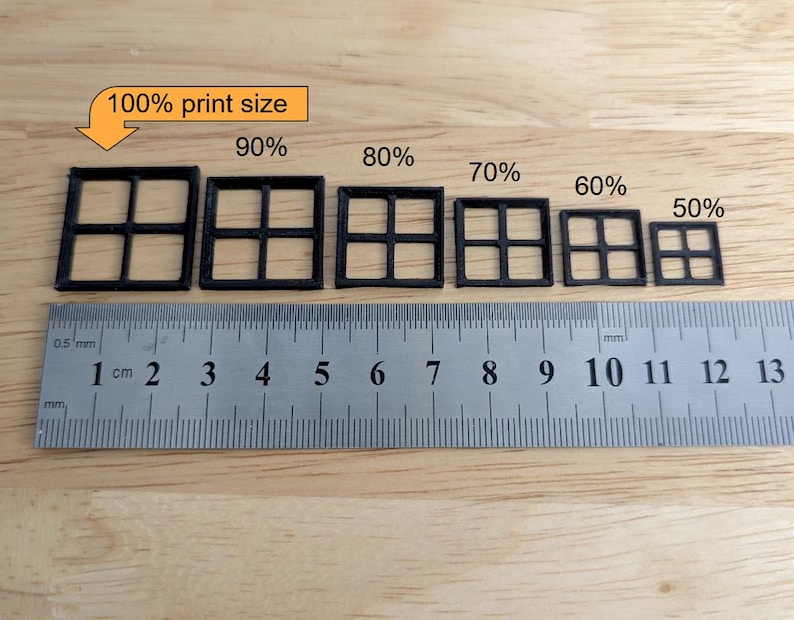 May include: A ruler with centimetre markings next to six black square window frame models of varying sizes, labelled from 50% to 100% print size. The text "100% print size" is in a yellow box.