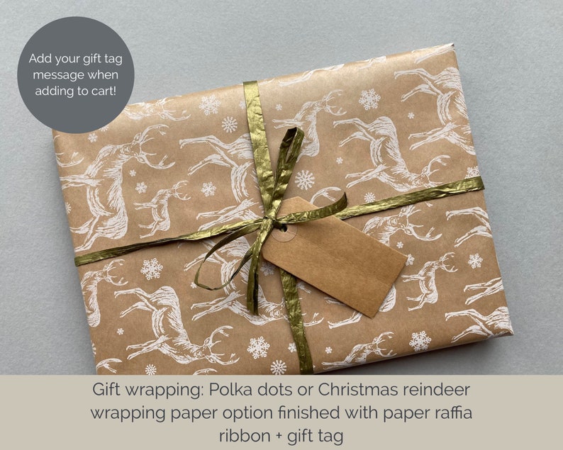 May include: A brown gift box wrapped in paper with a white reindeer pattern. The box is tied with a gold ribbon and a brown gift tag.