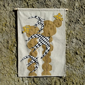 Peut inclure: Une tenture murale en tissu beige avec un motif d'oiseau stylisé brun et blanc et des accents de fleurs jaunes.