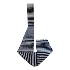 May include: Black and white striped rug with fringe on the ends. The rug is folded in the shape of a 'J'.