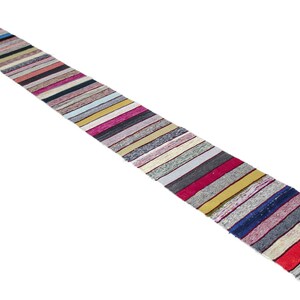 May include: A long, narrow, multi-colored rug with a striped pattern. The rug is made of woven fabric and has a fringe on the ends.