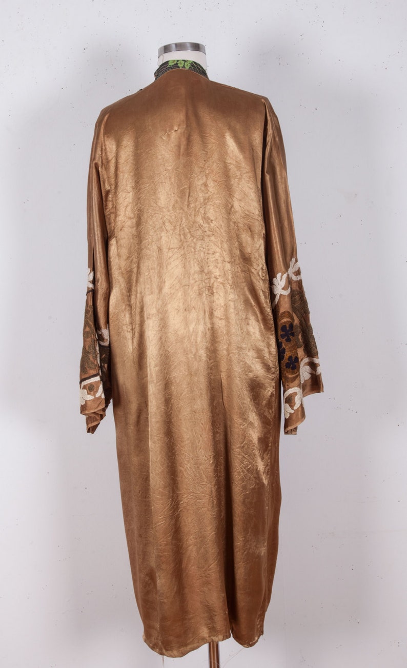 May include: A long, gold-colored robe with embroidered floral details on the sleeves. The robe is made of a silky fabric and has a simple, elegant design.