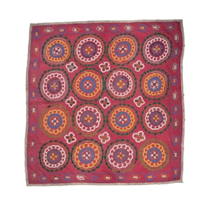Może przedstawiać: Czerwony materiał z powtarzającym się wzorem haftowanych kół w odcieniach różowego, żółtego, niebieskiego i zielonego.