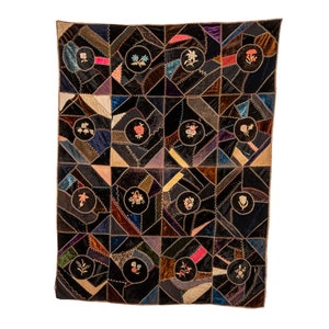 May include: A vintage quilt with a black background and a patchwork design of various colors and fabrics. The quilt is decorated with embroidered flowers in different colors.