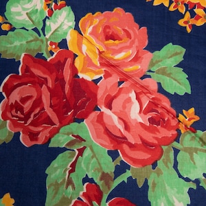 May include: A close-up of a navy blue fabric with a floral pattern. The fabric features red, pink, and yellow roses with green leaves.