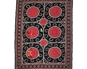 May include: A black and red embroidered textile with a repeating pattern of circles and floral designs. The textile has a border of small circles and a larger border of red and black.