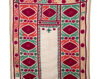 May include: A white cotton textile with a decorative embroidered border. The border features a repeating pattern of red, green, and pink geometric shapes. The centre of the textile is plain white.