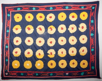 May include: A blue fabric quilt with a repeating pattern of yellow and red circles. The quilt has a red, green, and white border with a repeating pattern.