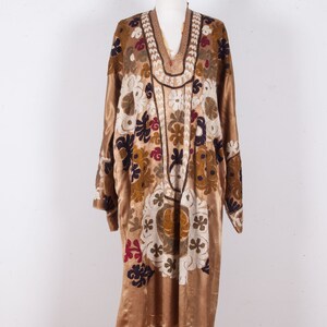 May include: A long, gold-colored robe with a V-neck and intricate floral embroidery in shades of white, brown, red, and blue.
