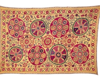 May include: A yellow fabric wall hanging with a repeating pattern of colorful floral medallions. The medallions are embroidered with pink, red, green, and purple thread.