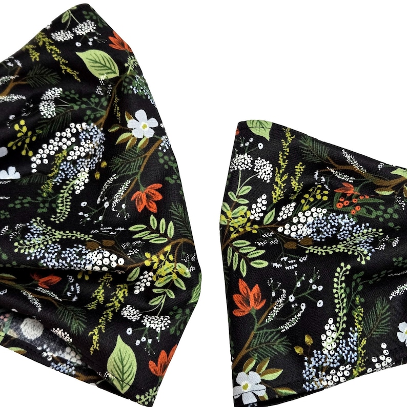 May include: Two black fabric headbands with a floral pattern. The pattern includes white, green, and orange flowers and foliage. The headbands are likely for fashion or hair accessories.