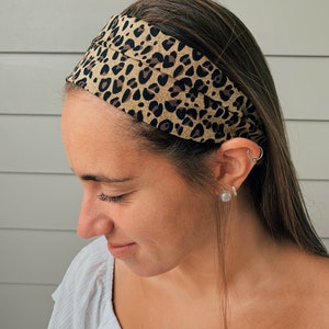 May include: A tan and black leopard print headband, scrunched to a narrow band, is worn on the head. The text "Scrunched to a narrow headband" is visible in the image.